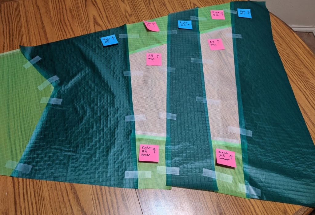 Dark green, neon, and mesh panels of a kite taped together, with sticky notes on each piece.